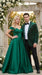 Man in a green plaid suit and woman in a green evening gown standing together outdoors with floral decorations.